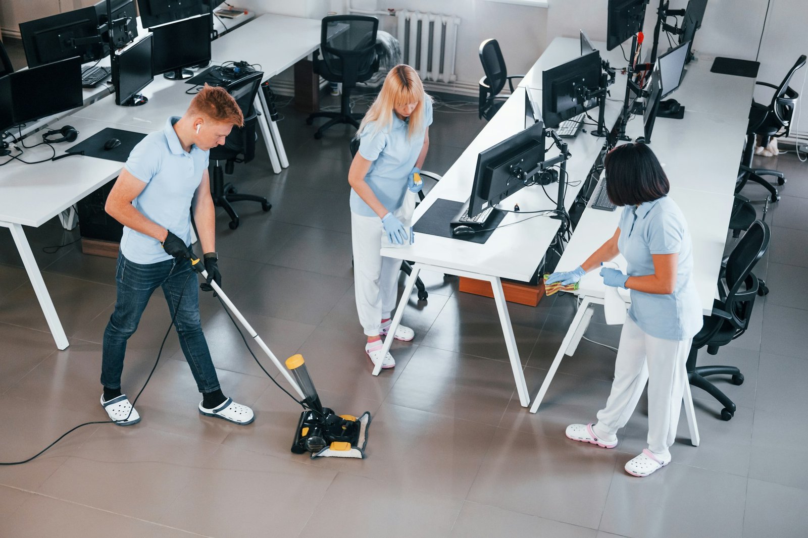 Cleans floor. Group of workers clean modern office together at daytime