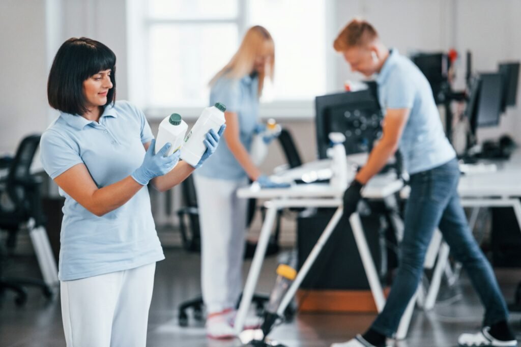 Group of workers clean modern office together at daytime